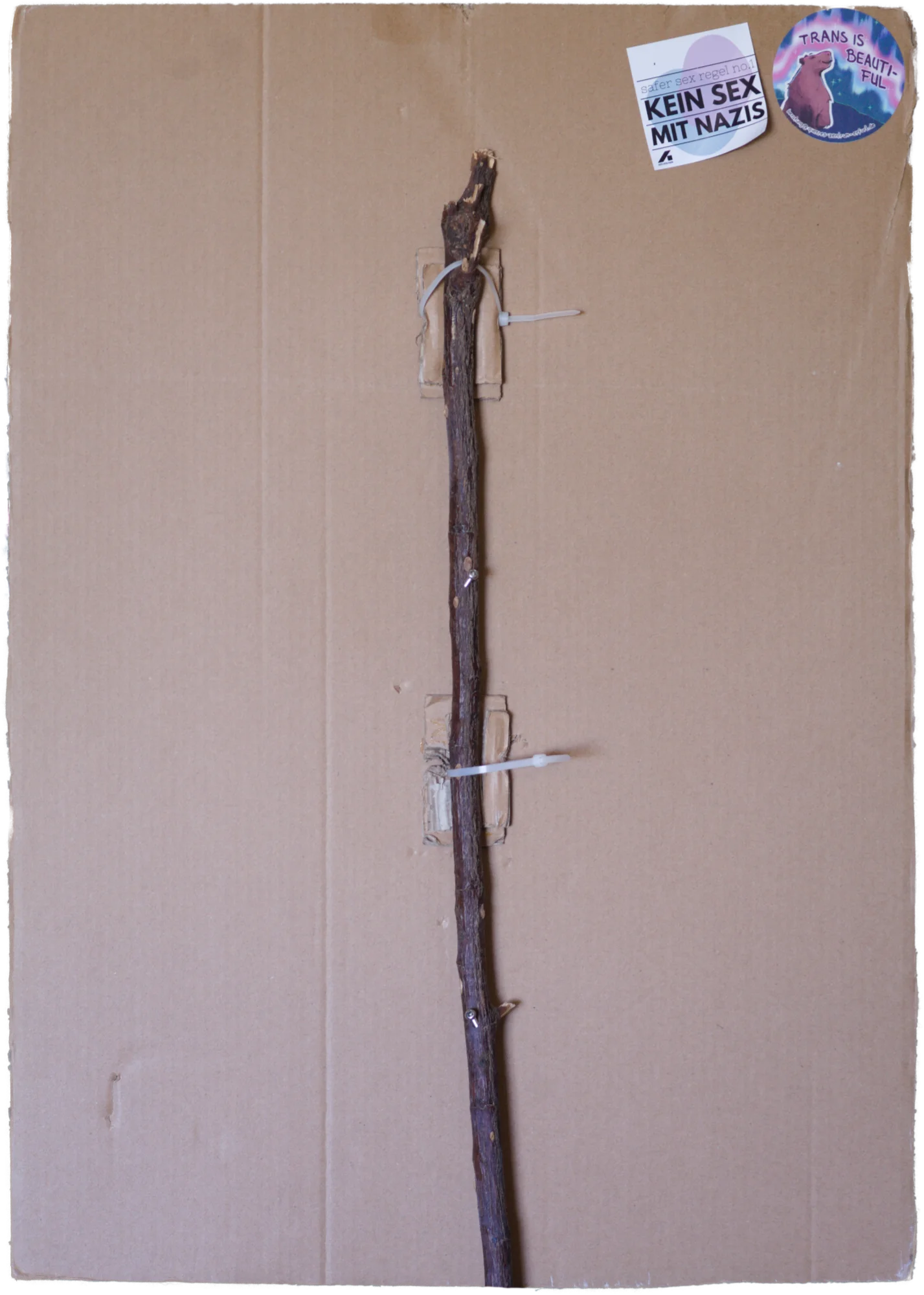 Back side of the poster with a couple of stickers and a pole attached